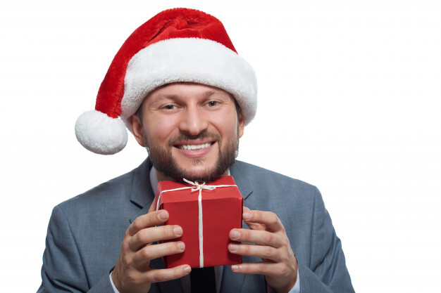 excited cheerful businessman holding up a small christmas gift box to his face smiling 7502 5390